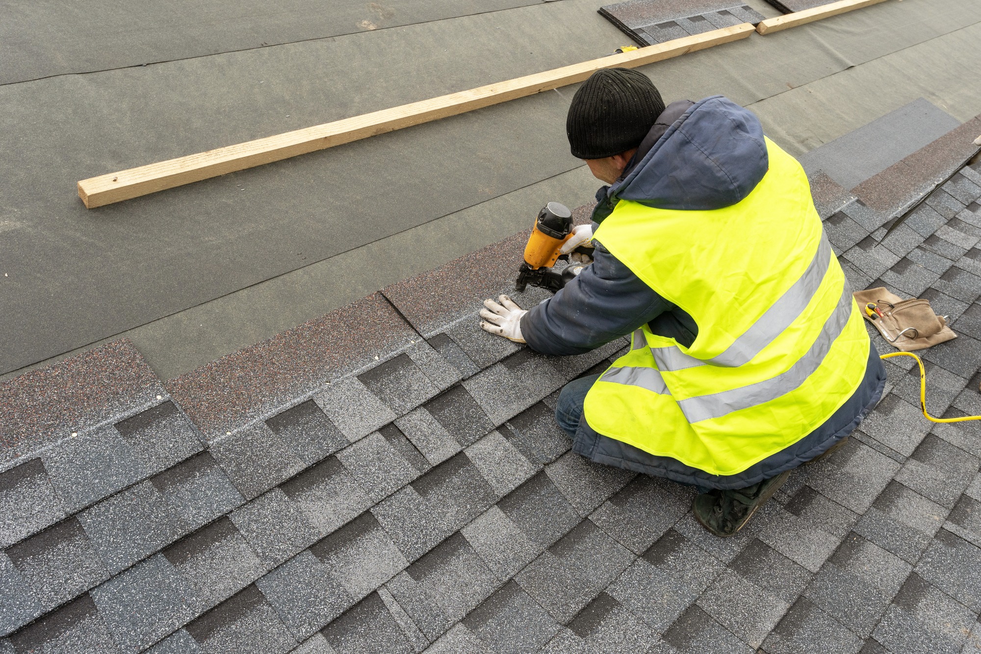 Qualified workman in uniform work wear using air or pneumatic nail gun